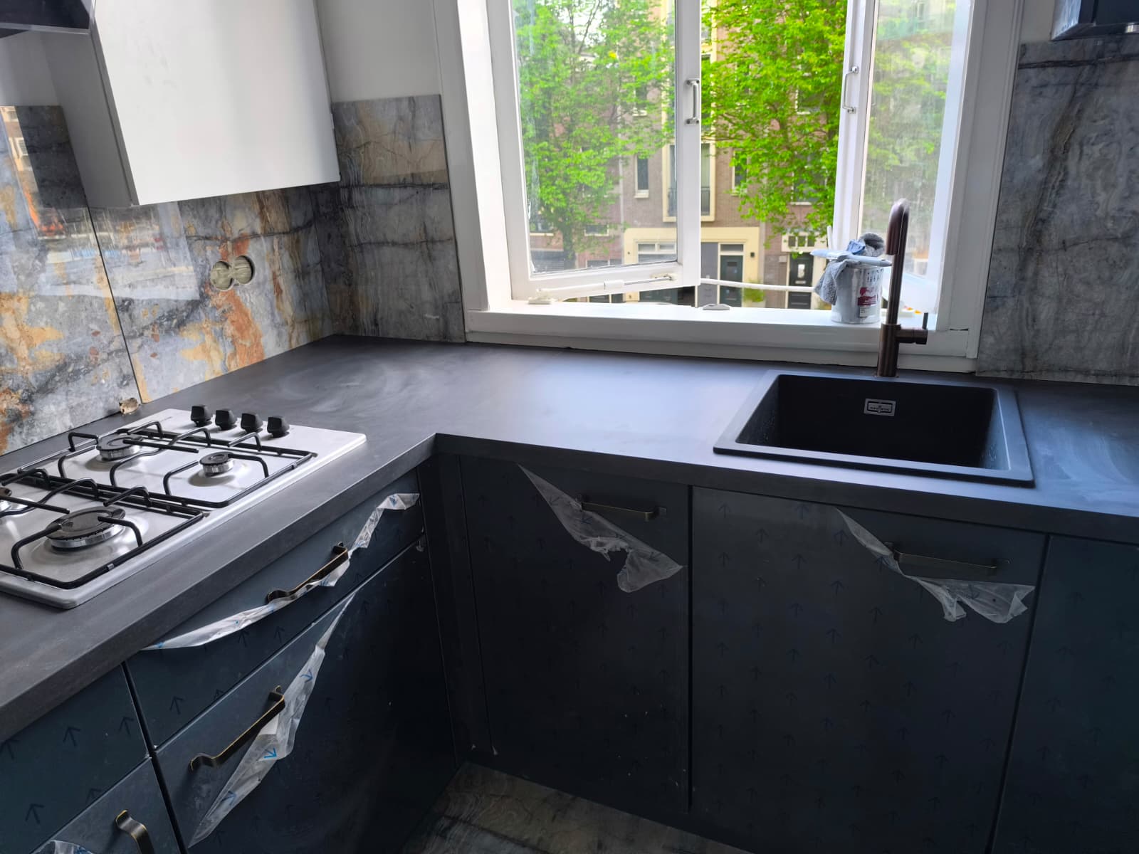 Donkere keuken met marmer-look achterwand geplaatst door Klusbedrijf 360 in Amsterdam